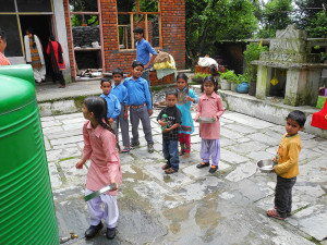 The kids have just had their lunch and are washing their plates.